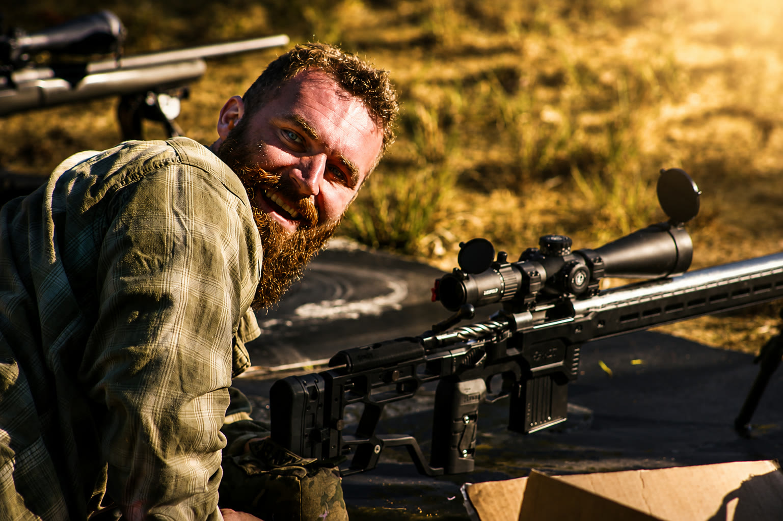 Shooter grinning behind a Helanbak precision bolt rifle at the range